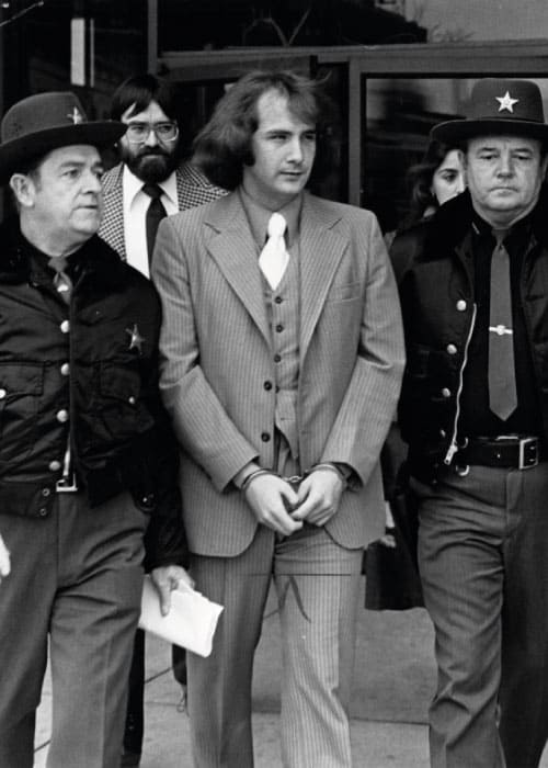 Imagem em preto e branco de Billy Milligan sendo escoltado por dois policiais