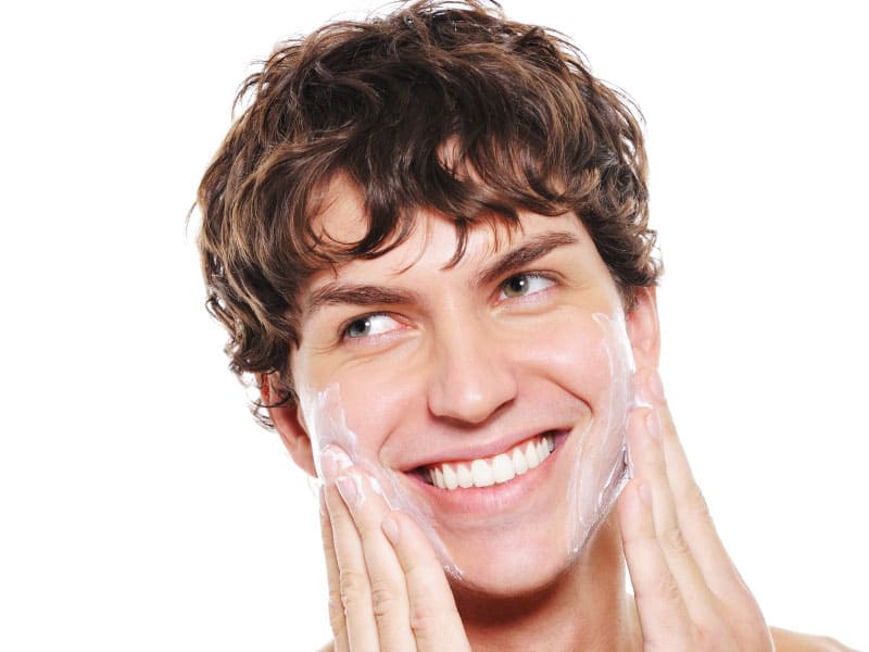 Homem sorridente aplicando cosmético nas bochechas