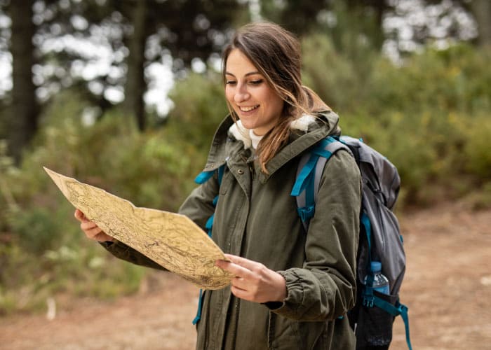 mulher jovem vestida com casaco de aventura e mapa na mão